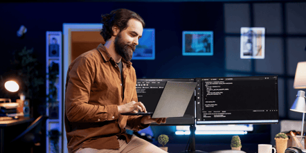 AI professional sitting on a desk looking at a laptop