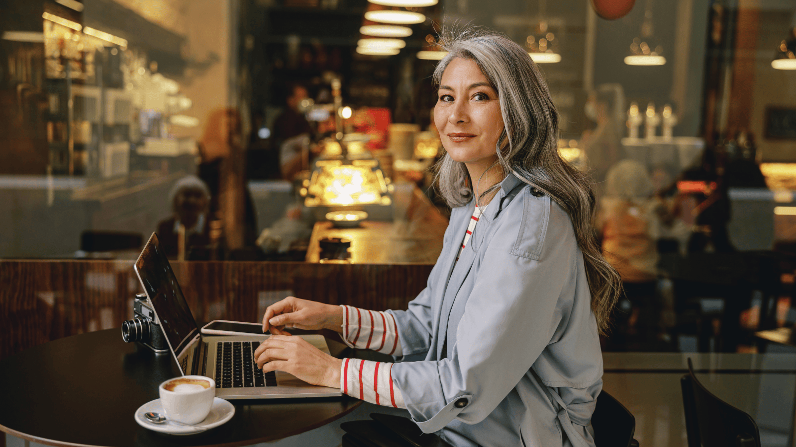 Middle-aged female writer sits with a laptop in a cafe
