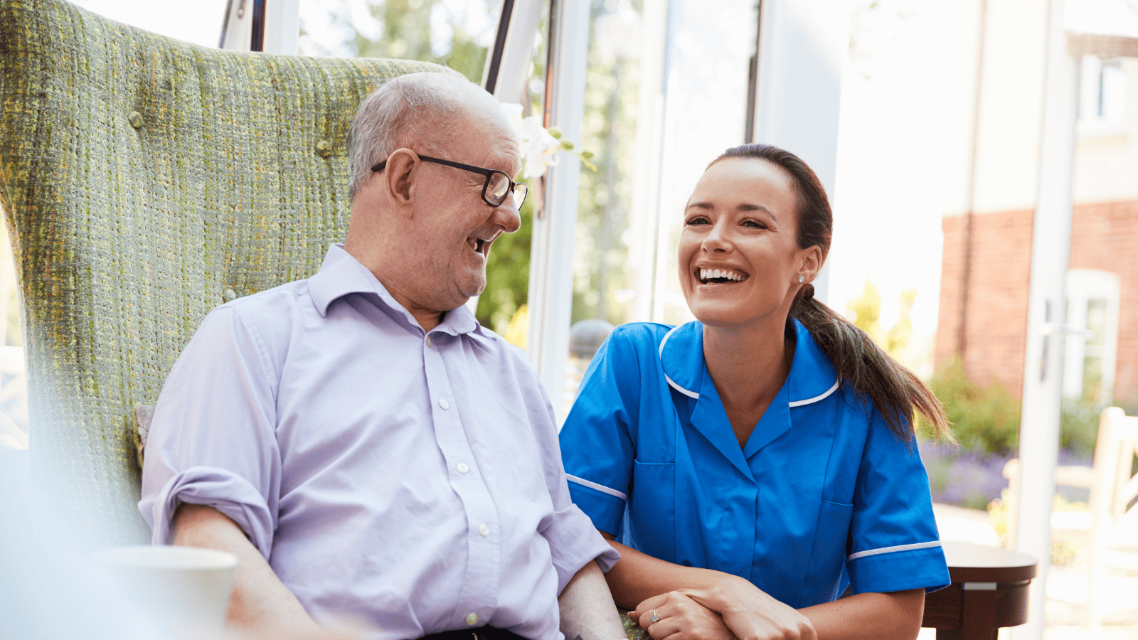 Elderly male dementia patient and his female care worker laugh together