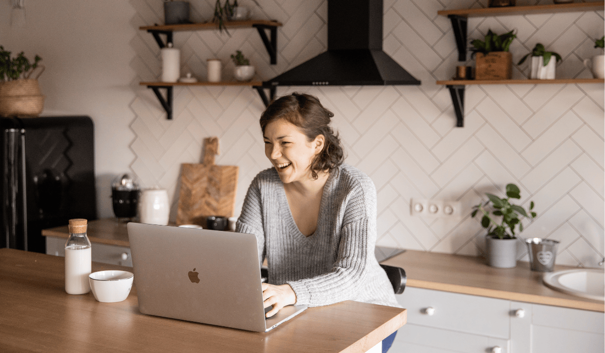 Hull Online prospective student smiling using a laptop in kitchen