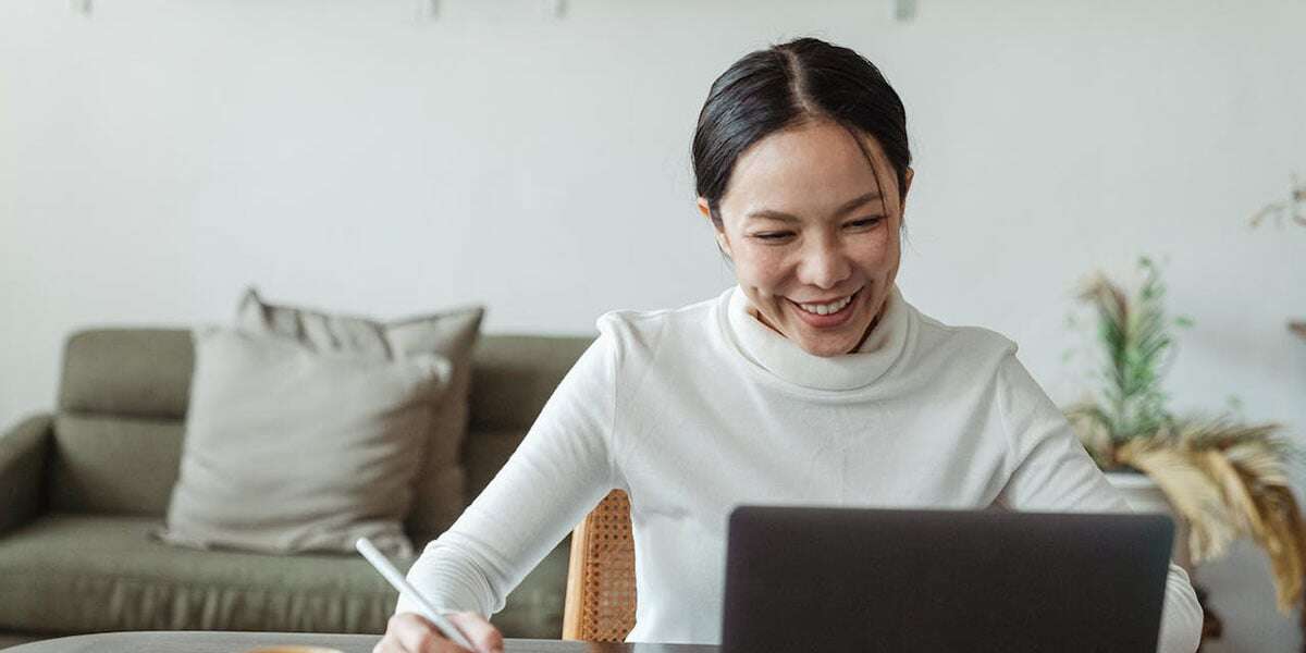 Woman holding a pen looking at a laptop