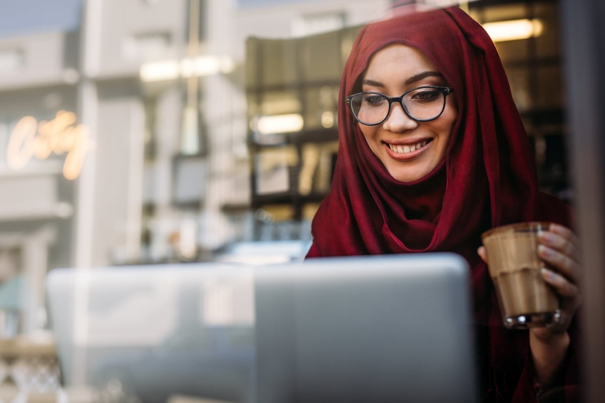 Hull Online student working on a laptop holding a coffee